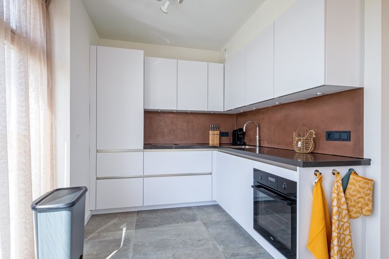 Moderne Kueche in der Ferienunterkunft De Zuidbunder auf Texel mit schlichten weissen Schraenken.