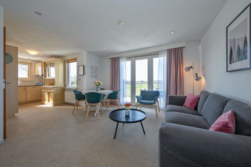 Lichte woonkamer van Huisje 7 in De Dennen, Texel met comfortabele zithoek en uitzicht op de natuur van de Waddeneilanden.