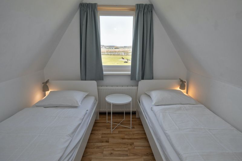 Slaapkamer met twee eenpersoonsbedden in Huisje 7 in De Dennen, Texel met uitzicht op de groene omgeving van de Waddeneilanden.