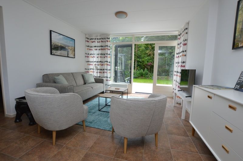 Lichte woonkamer van Vakantiehuis de Parel 182 in De Dennen, Texel met uitzicht op de tuin.