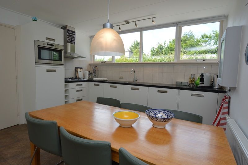 Eetkamer in Vakantiehuis de Parel 182, De Dennen, Texel met houten tafel en stijlvolle stoelen.