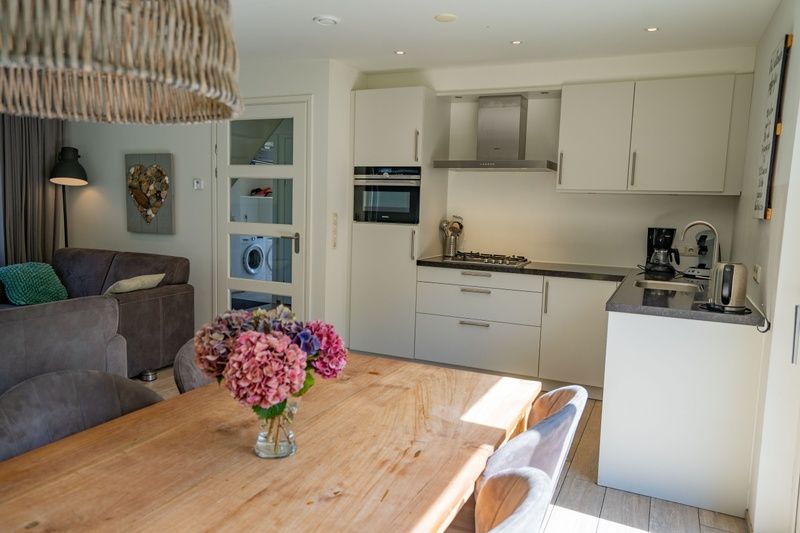 Moderne Kueche des Ferienhauses de Parel 150 in De Dennen, Texel mit Essecke.