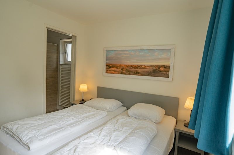Schlafzimmer mit eigenem Badezimmer im Ferienhaus de Parel 150 in De Dennen, Texel.