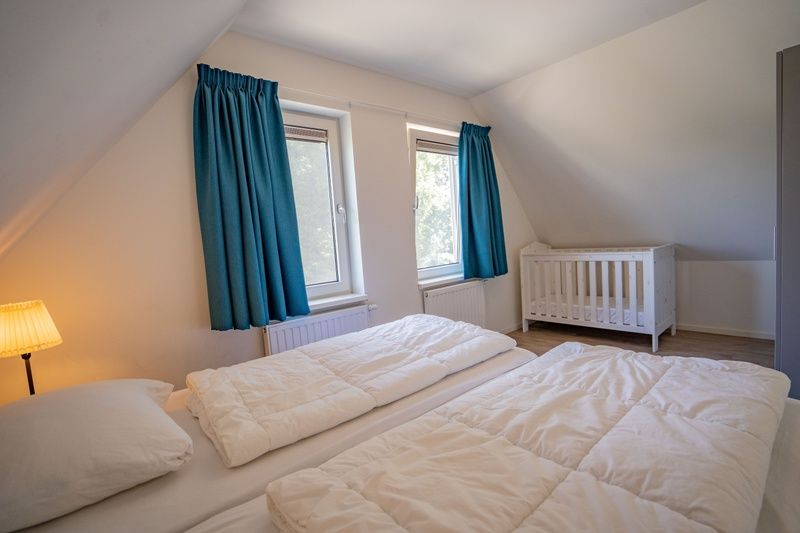 Geraeumiges Schlafzimmer mit Kinderbett im Ferienhaus de Parel 150 in De Dennen, Texel.