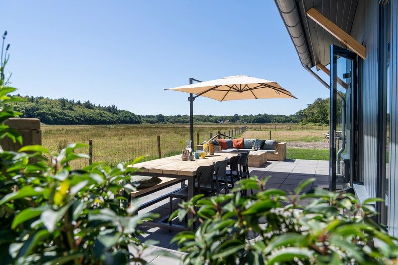 Geraeumige Terrasse des Ferienhauses 2 in De Dennen, Texel mit Blick auf die Natur und die Watteninseln.