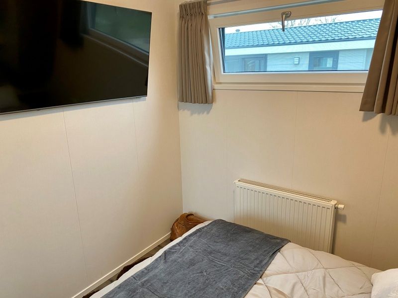 Slaapkamer met televisie in Vakantiepark de Bremakker - Bosveld 148, De Dennen, Texel voor ultiem comfort en ontspanning.