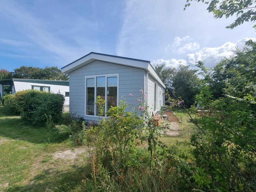 Vakantiehuis bij Vakantiepark de Bremakker, Bosveld 135 in De Dennen, Texel, omgeven door groene natuur en bloemen.