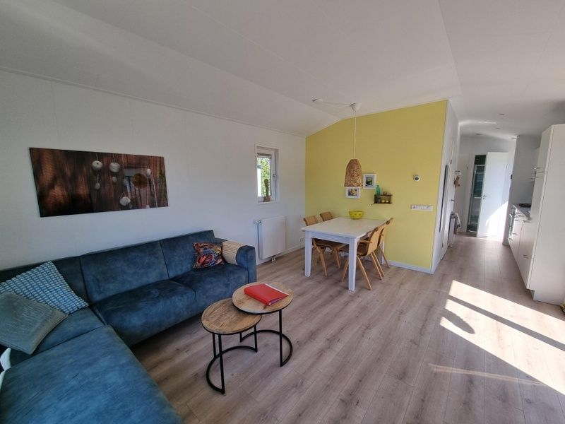 Gezellige woonkamer in Vakantiepark de Bremakker, Bosveld 135, De Dennen, Texel, met comfortabele bank en eethoek.