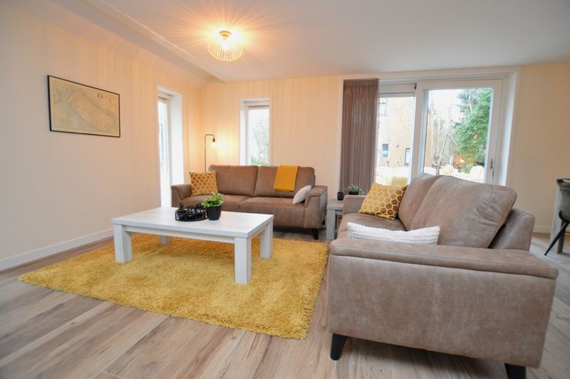 Helles Wohnzimmer im Ferienhaus De Nagtegaal 23, De Dennen Texel, mit moderner Einrichtung und Blick auf den Garten.