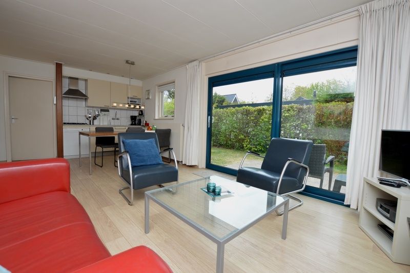 Offener Wohnbereich im Ferienhaus De Parel 192, De Dennen, Texel mit Zugang zum Garten und einer voll ausgestatteten Kueche.