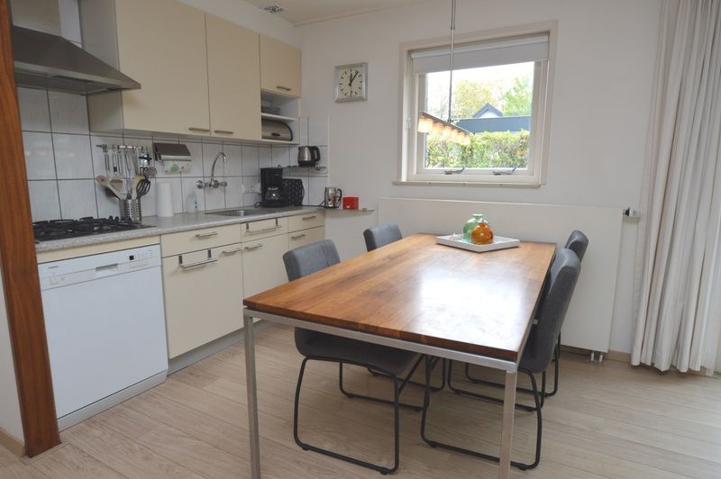 Kueche im Ferienhaus de Parel 192, De Dennen, Texel mit modernen Geraeten und einem grossen Esstisch.