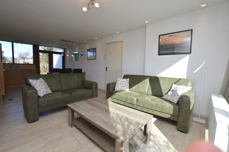 Geraeumiges Interieur des Ferienhauses de Parel 198 in De Dennen, Texel, mit moderner Einrichtung und Gartenblick.