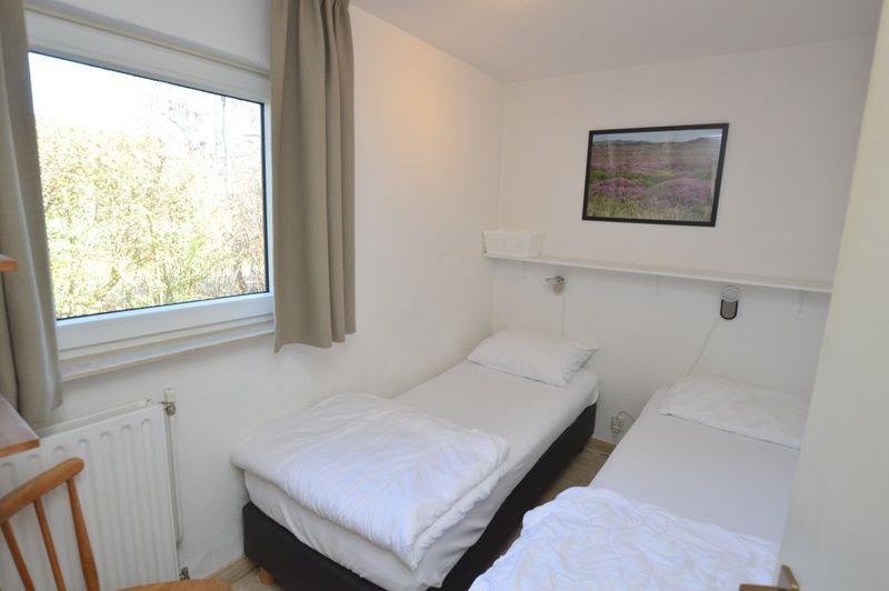 Gemuetliches Schlafzimmer im Ferienhaus de Parel 198 in De Dennen, Texel mit zwei Einzelbetten und Blick auf die Natur.