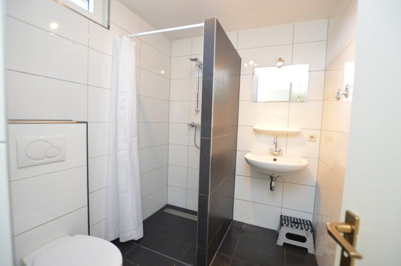 Modernes Badezimmer im Ferienhaus de Parel 198 in De Dennen, Texel, mit begehbarer Dusche und stilvoller Einrichtung.