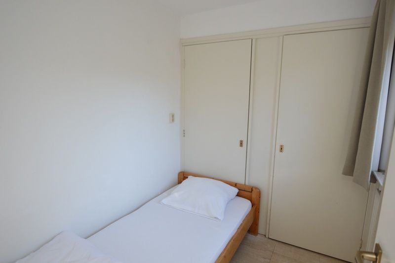 Einfaches Einzelzimmer im Ferienhaus de Parel 198 in De Dennen, Texel, mit weisser Einrichtung und praktischem Stauraum.