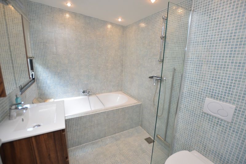 Luxurioeses Badezimmer des Ferienhauses 't Hoogelandt 202 - Aan Zee, Texel, mit einer geraeumigen Badewanne und einer modernen Dusche.