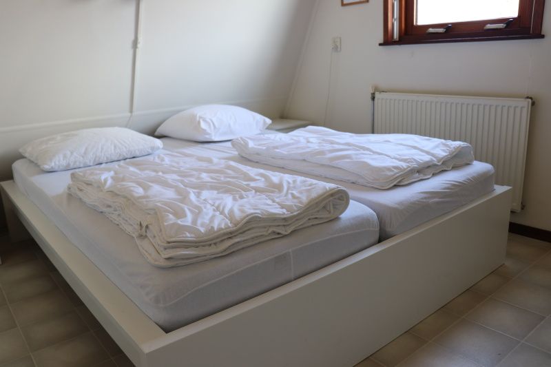 Slaapkamer in Vakantiehuis Gortersmient 330 in De Dennen, Texel met tweepersoonsbed en lichte inrichting.