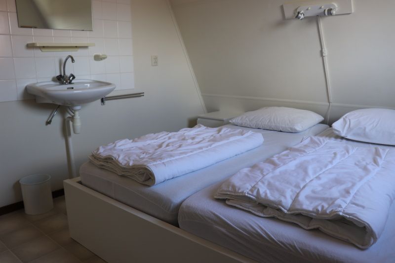 Tweede slaapkamer in Vakantiehuis Gortersmient 330 in De Dennen, Texel met wastafel en comfortabel bed.