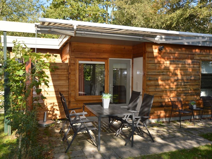 Veranda van Vakantiehuis De Nagtegaal 19 in De Dennen Texel met houten gevel en tuinmeubilair.