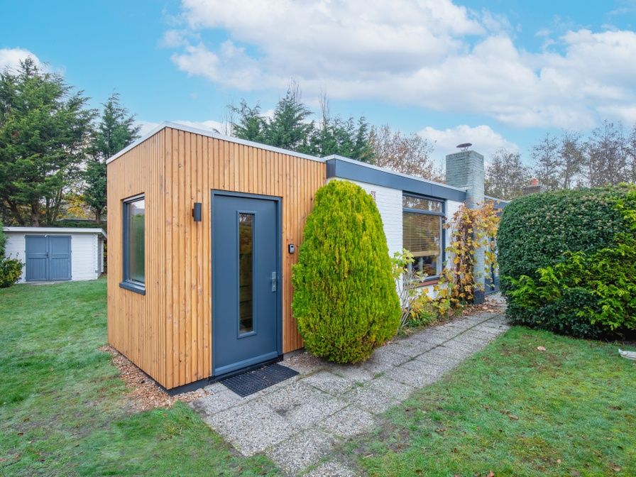 Bungalowpark 't Luwe Land - 7B - De Wijnhof in De Dennen, Texel, met groene tuin en helderblauwe lucht.