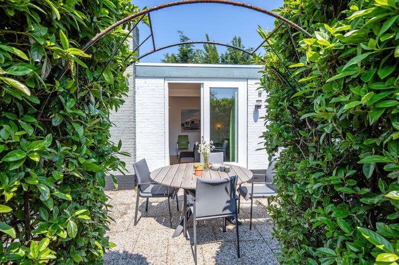 Eethoek met uitzicht op de tuin in Bungalowpark 't Luwe Land - 7B - De Wijnhof, Texel, met veel natuurlijk licht.