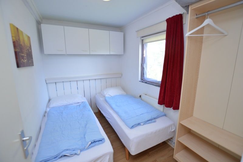 Comfortabele slaapkamer in Vakantiehuis de Parel 222, Texel met aangenaam licht en opbergruimte.