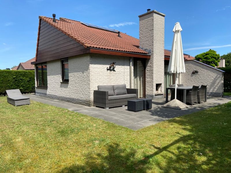 Buitenzijde van Vakantiehuis Gortersmient 356, De Dennen Texel, met terras en tuinmeubilair onder een parasol.