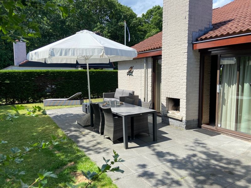 Zonnig terras bij Vakantiehuis Gortersmient 356, De Dennen Texel, met eethoek en groene omgeving.
