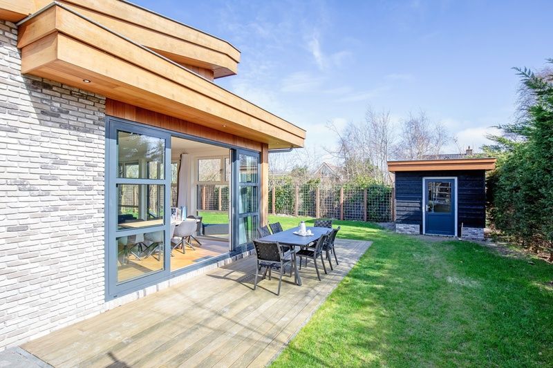Side view of Holiday Home De Vlinder in De Dennen, Texel, with sunny terrace and green garden.