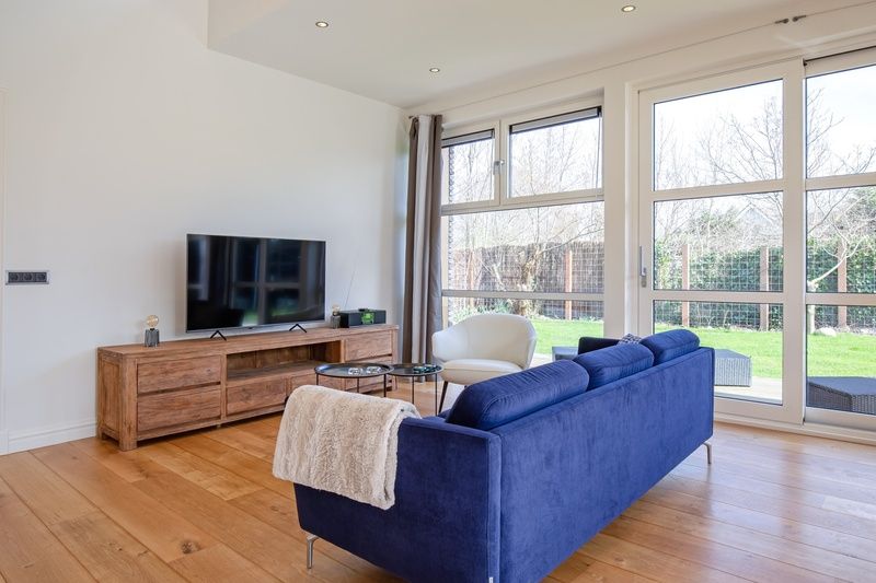Bright living room in Holiday Home De Vlinder, Texel, with modern furnishings and garden views.