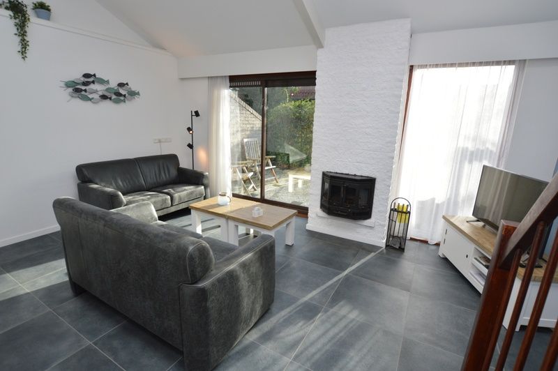 Ruime woonkamer van vakantiehuis Gortersmient 240, Bungalowpark Gortersmient, De Dennen Texel met open haard en grote ramen.