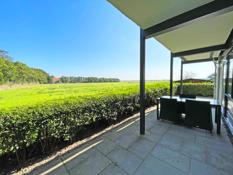 Uitzicht vanaf het terras van Appartement Bos en Duin 12, De Dennen, Texel, met weidse velden en bossen.