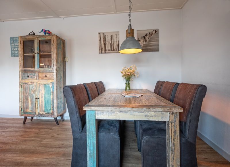 Gemuetliches Esszimmer im Ferienhaus Flora, gelegen in De Dennen, Texel. Entspannte Atmosphaere mit Holzmoebeln und rustikaler Einrichtung.