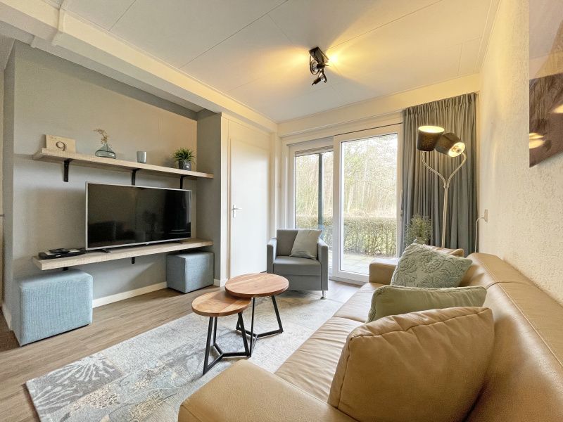 Stilvolles Wohnzimmer des Appartements Bos en Duin 14, Texel, mit Flachbildfernseher und Zugang zur Terrasse.