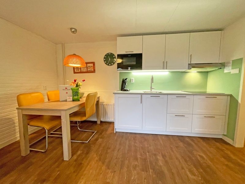 Moderne keuken in Appartement Bos en Duin 15, De Dennen, Texel met eethoek en sfeervolle verlichting.