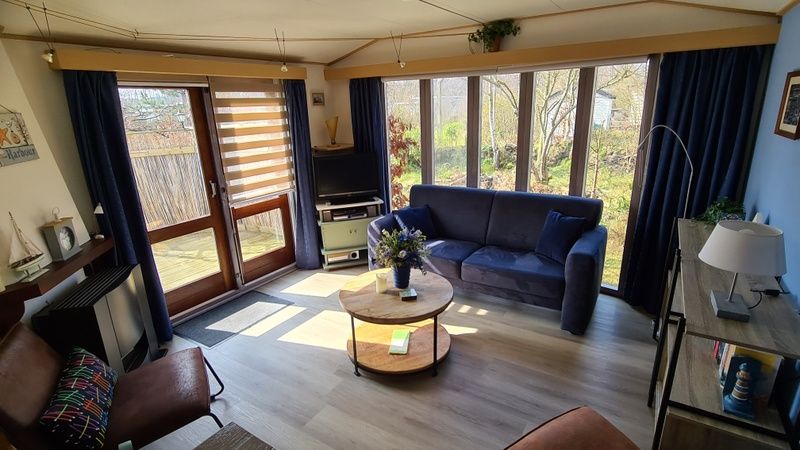 Wohnzimmer im Vakantiepark De Bremakker, Texel, mit bequemen Sitzgelegenheiten und grossen Fenstern fuer eine tolle Aussicht.