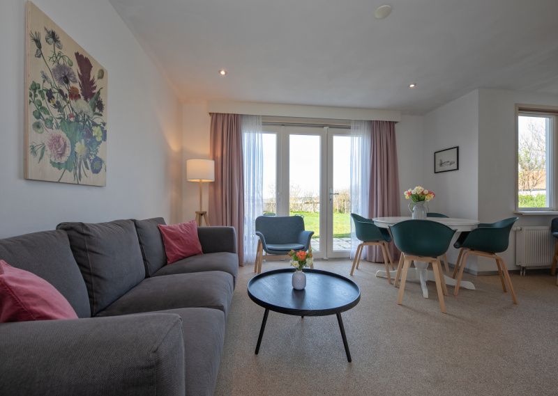 Gemuetliches Wohnzimmer von Cottage 6 in De Dennen, Texel, mit bequemer Sitzecke und Gartenblick.