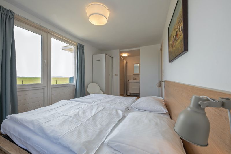 Geraeumiges Schlafzimmer in Cottage 6, Texel mit Doppelbett und schoener Aussicht auf die Natur.