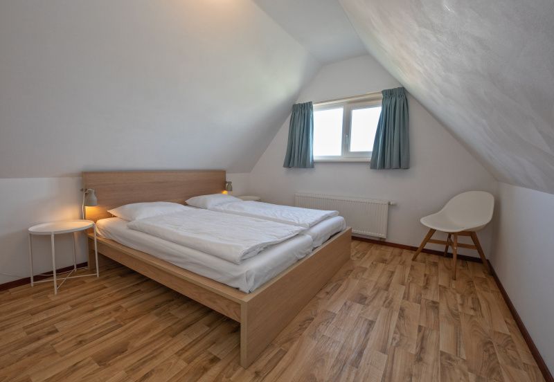 Schlafzimmer im Dachgeschoss in Haus 6, Texel. Gemuetliche Atmosphaere mit Holzboden und Dachfenster.