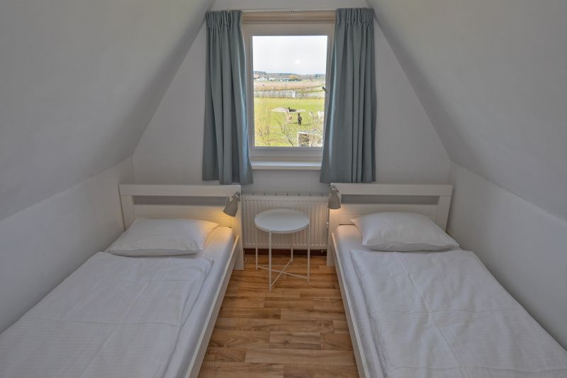 Zweites Schlafzimmer in Cottage 6, De Dennen, Texel mit zwei Einzelbetten und Blick auf die Landschaft.