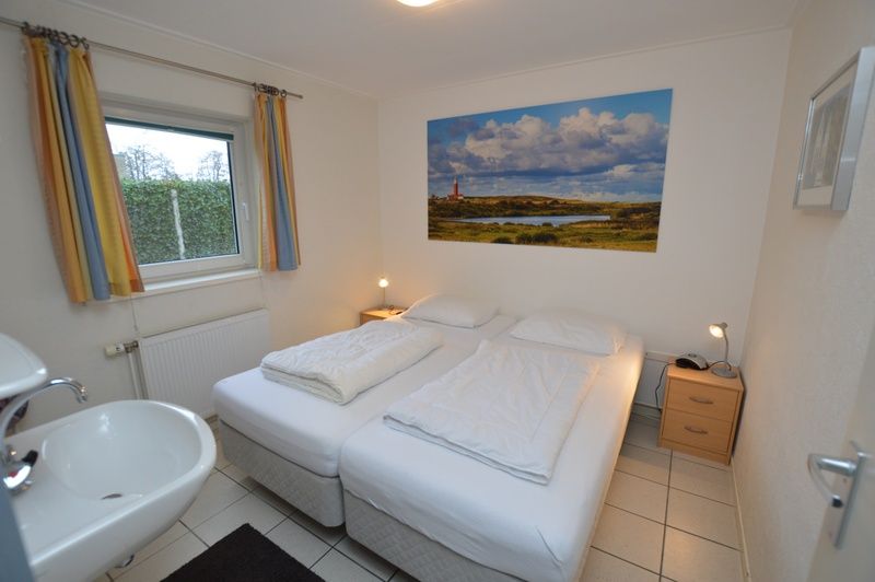 Sfeervolle slaapkamer in Vakantiehuis de Parel 194, De Dennen, Texel met tweepersoonsbed en kunstwerk.