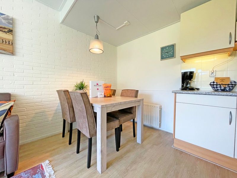 Gemuetliche Essecke im Apartment Bos en Duin 31, De Dennen, Texel mit Holztisch und bequemen Stuehlen.