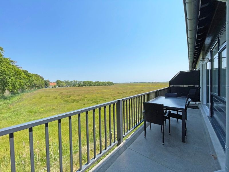 Geraeumiger Balkon im Appartement Bos en Duin 31, De Dennen, Texel mit Panoramablick auf die gruene Umgebung.