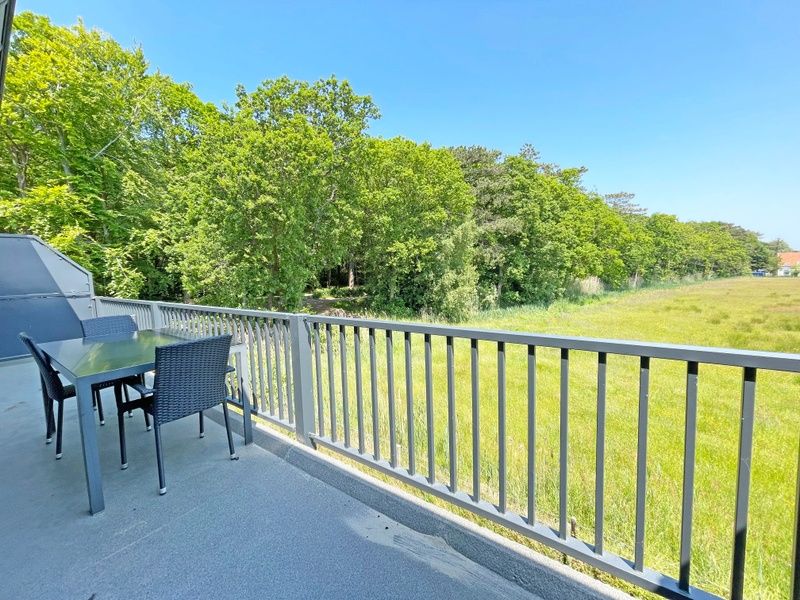 Terrasse mit Sitzgelegenheit im Apartment Bos en Duin 31, De Dennen, Texel, umgeben von ueppiger Natur.