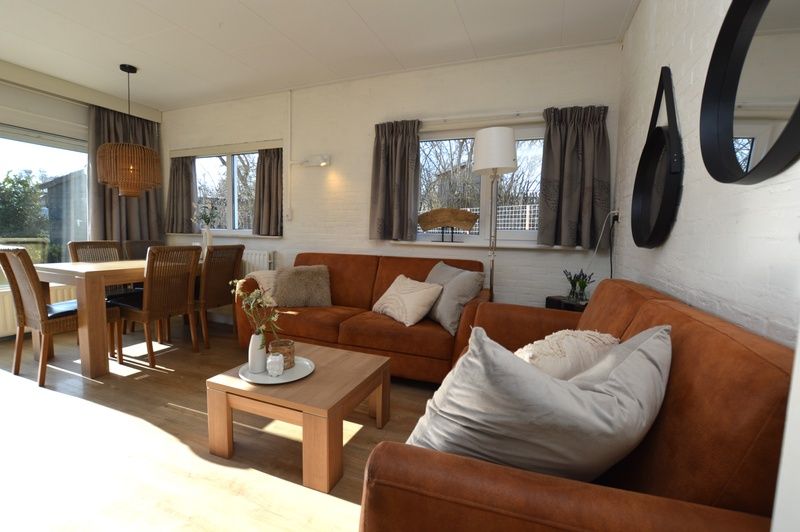 Lichte woonkamer van Bungalow Uterste Coogh 96 in De Dennen, Texel, met comfortabele banken en eethoek op de Waddeneilanden.
