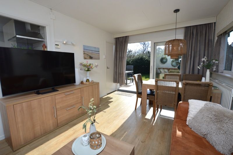 Gezellige zithoek in Bungalow Uterste Coogh 96, De Dennen, Texel, met uitzicht op de tuin en veel natuurlijk licht.