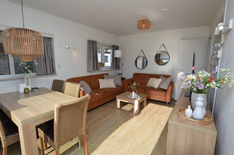 Stijlvolle binnenruimte van Bungalow Uterste Coogh 96 in De Dennen, Texel, met eethoek en gezellige zithoek.