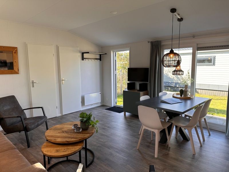 Gemuetliches Wohnzimmer im Ferienhaus Vakantiepark de Bremakker, Bosveld 128, De Dennen, Texel, mit moderner Einrichtung und Blick auf den Garten.