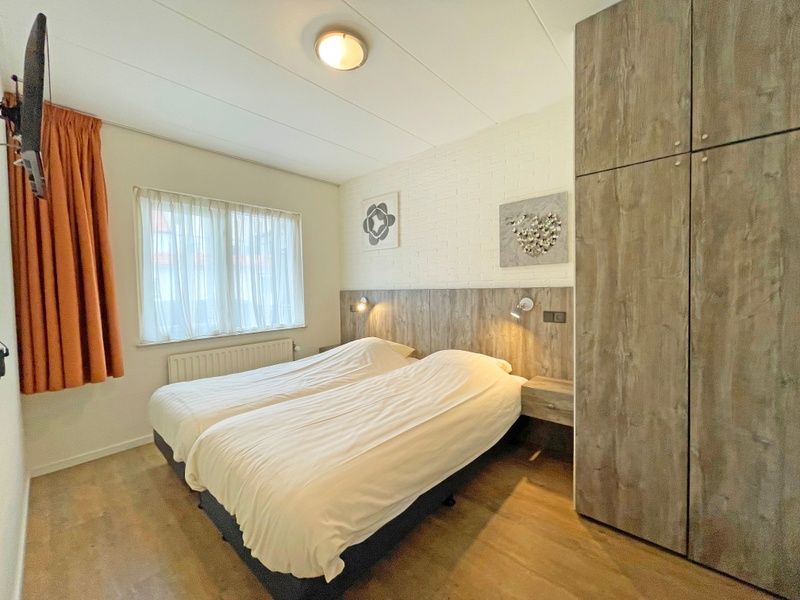 Slaapkamer van Appartement Bos en Duin 10, Texel met twee comfortabele bedden en warme inrichting.