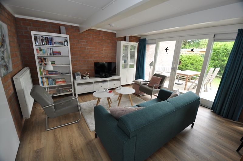 Gezellige woonkamer in Bungalow Verste Coogh 62, De Dennen, Texel met comfortabele zithoek en toegang tot het terras.